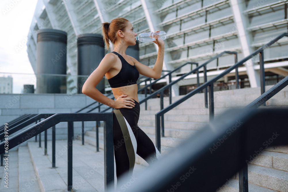 Portraits of a young sportswoman exercising outdoors. Beautiful woman in sportswear performs sports exercises in urban environment. Concept of sport, active and healthy lifestyle.