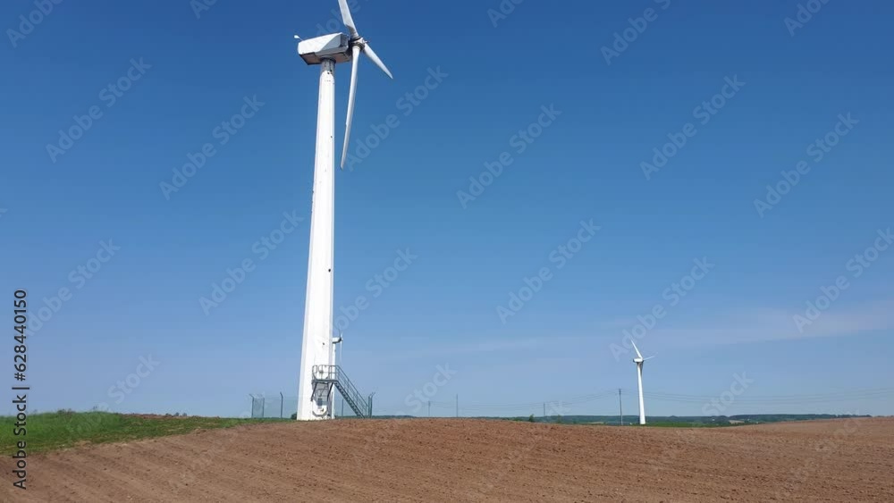 The rotor of a wind turbine rotates rapidly against the blue sky. Tilt up shot taken on a sunny day. The rotor of a wind turbine rotates rapidly against the blue sky. Tilt up shot taken on a sunny day.