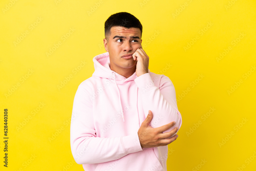 Young handsome man over isolated yellow background is a little bit nervous Young handsome man over isolated yellow background is a little bit nervous