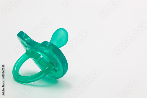 Turquoise pacifier for a newborn on a white insulated background.