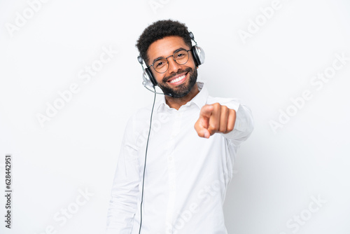 Telemarketer Brazilian man working with a headset isolated on white background points finger at you with a confident expression