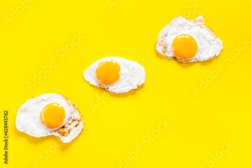 Fried eggs pattern on yellow background, top view. Breakfast concept
