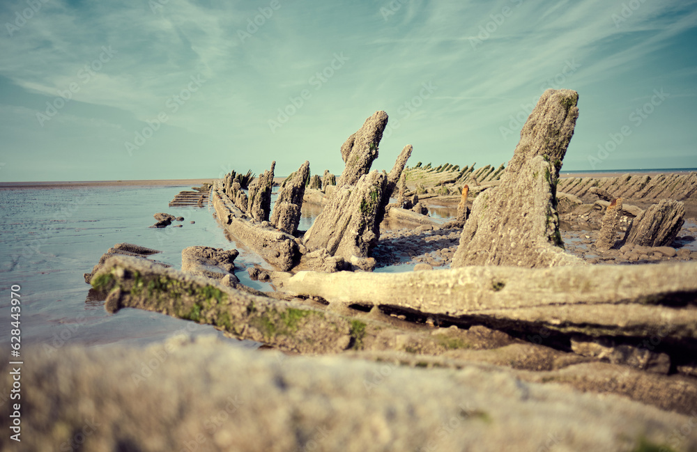 An old historic wooden shipwreck vessel carcass exposed on a desolate tropical island beach. Maritime and exploration disaster. Pirate boats from historical days. Beached ship wrecks