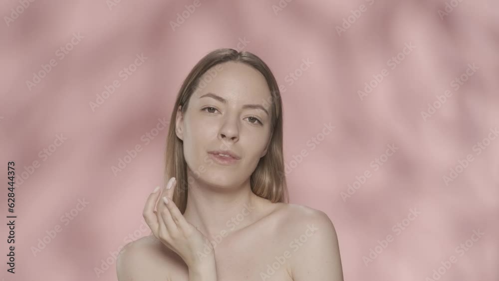 A woman touches her lips while moisturizing them in the studio on a pink background close up. A woman applies lip balm, natural hydration, healing of dry, chapped lips. HDR BT2020 HLG Material. A woman touches her lips while moisturizing them in the studio on a pink background close up. A woman applies lip balm, natural hydration, healing of dry, chapped lips. HDR BT2020 HLG Material.