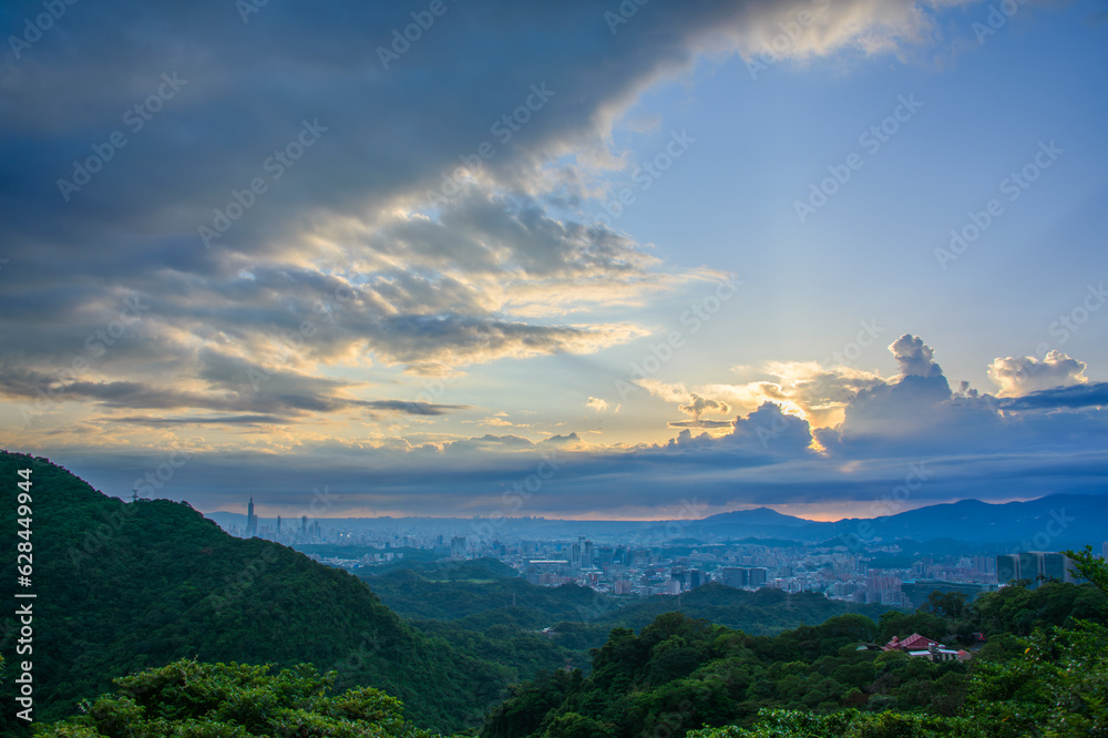 Obraz premium Awe-Inspiring Views of the Sun Shining Through the Clouds and the Dynamic Sky. View of the urban landscape from Dajianshan Mountain, New Taipei City, Taiwan