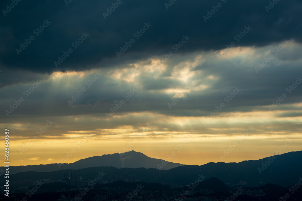 Dynamic Crepuscular Ray and silhouette of Guanyin Mountain. View of the urban landscape from Dajianshan Mountain, New Taipei City.