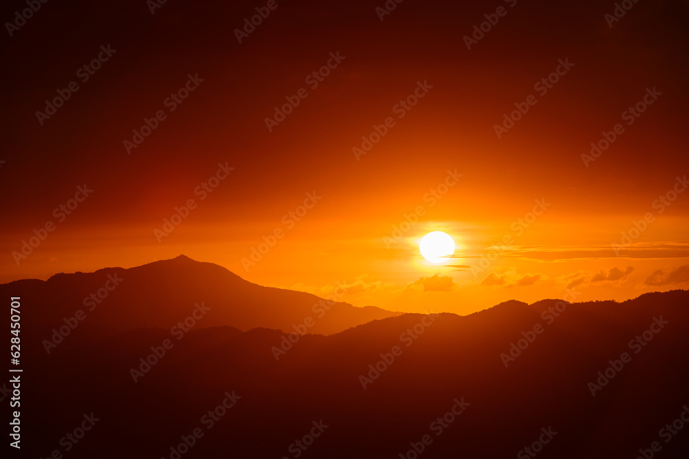 Fototapeta premium The orange-red sunset is covered by clouds as it moves towards the horizon. View of the urban landscape from Dajianshan Mountain, New Taipei City.