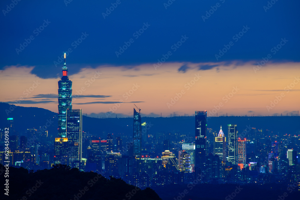 Fototapeta premium At dusk, the night view of Taipei gradually brightens. Dynamic clouds. View of the urban landscape from Dajianshan Mountain, New Taipei City.