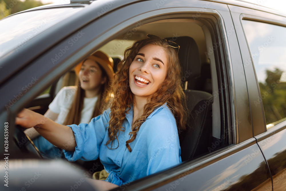 Portrait of two young women on a car trip having fun, smiling, chatting together, enjoying nature. Active lifestyle, travel, tourism, nature. Portrait of two young women on a car trip having fun, smiling, chatting together, enjoying nature. Active lifestyle, travel, tourism, nature.