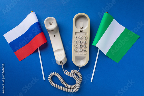 An old telephone and two flags on a blue background, a concept on the topic of telephone conversations between Russia and Niger