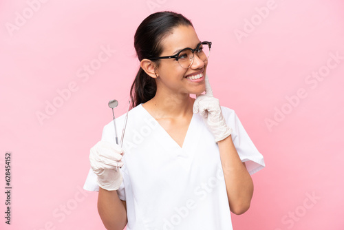 Dentist Colombian woman isolated on pink background thinking an idea while looking up