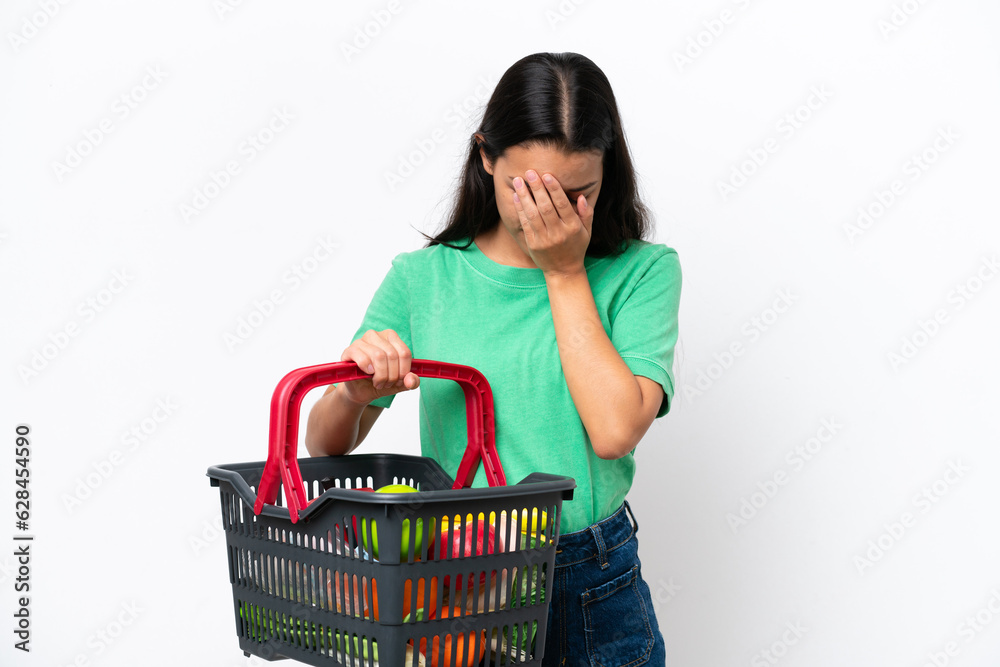 Young Colombian woman holding a shopping basket full of food isolated on white background with tired and sick expression Young Colombian woman holding a shopping basket full of food isolated on white background with tired and sick expression