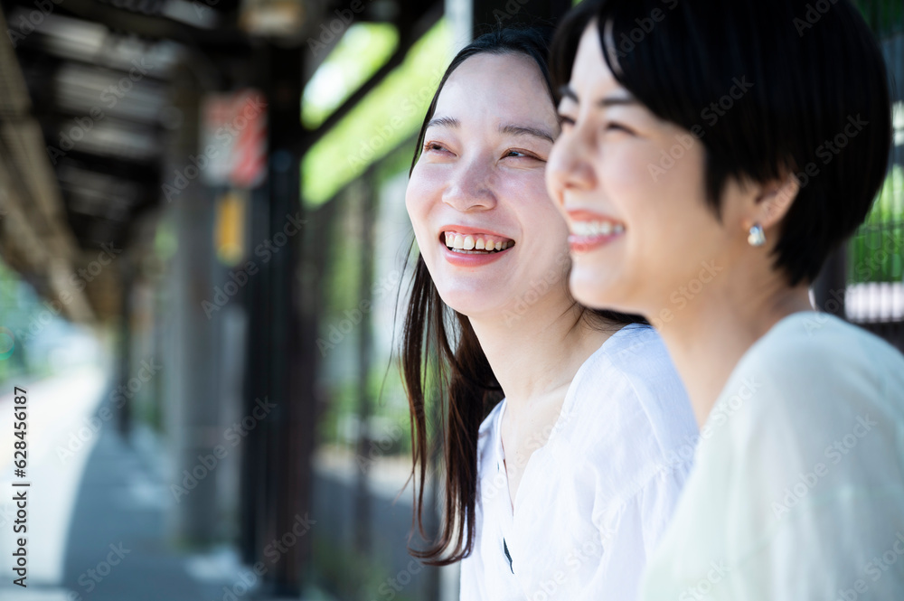 Two young, beautiful Asian women happily chatted at the station around their destination. Tourism and lifestyles Two young, beautiful Asian women happily chatted at the station around their destination. Tourism and lifestyles