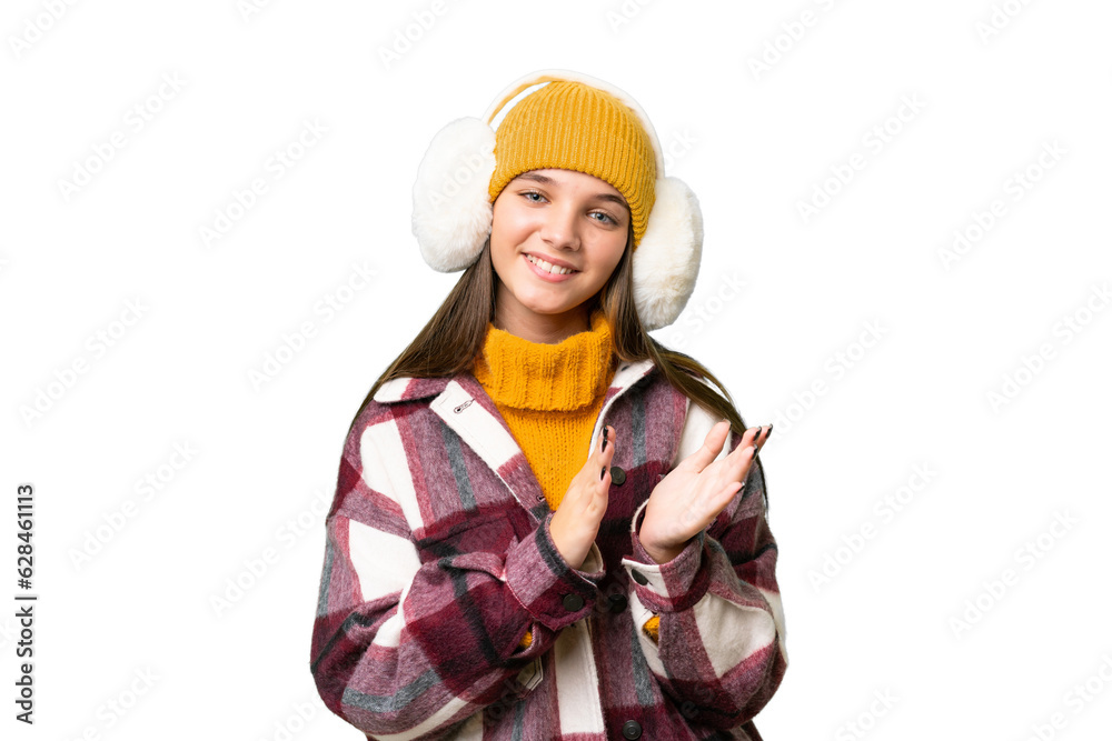 Teenager caucasian girl wearing winter muffs over isolated background applauding after presentation in a conference Teenager caucasian girl wearing winter muffs over isolated background applauding after presentation in a conference