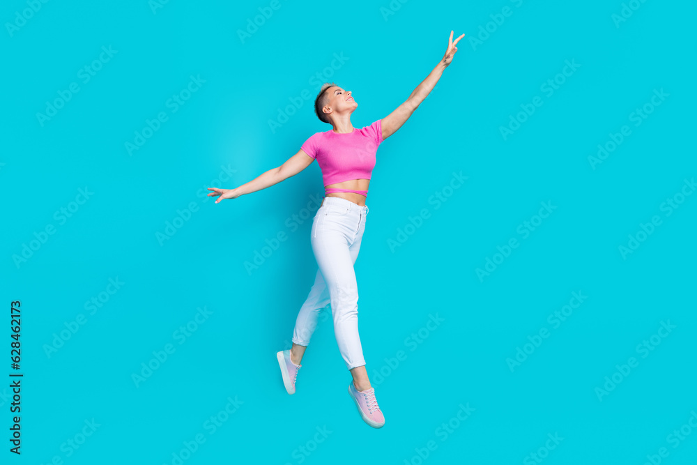 Full size photo of attractive young woman raise hand flying jump dressed stylish pink clothes isolated on cyan color background