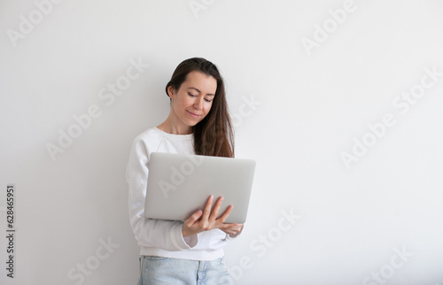 Young millennial woman wearing black hat using laptop, working online, white background. Copy space left and right.