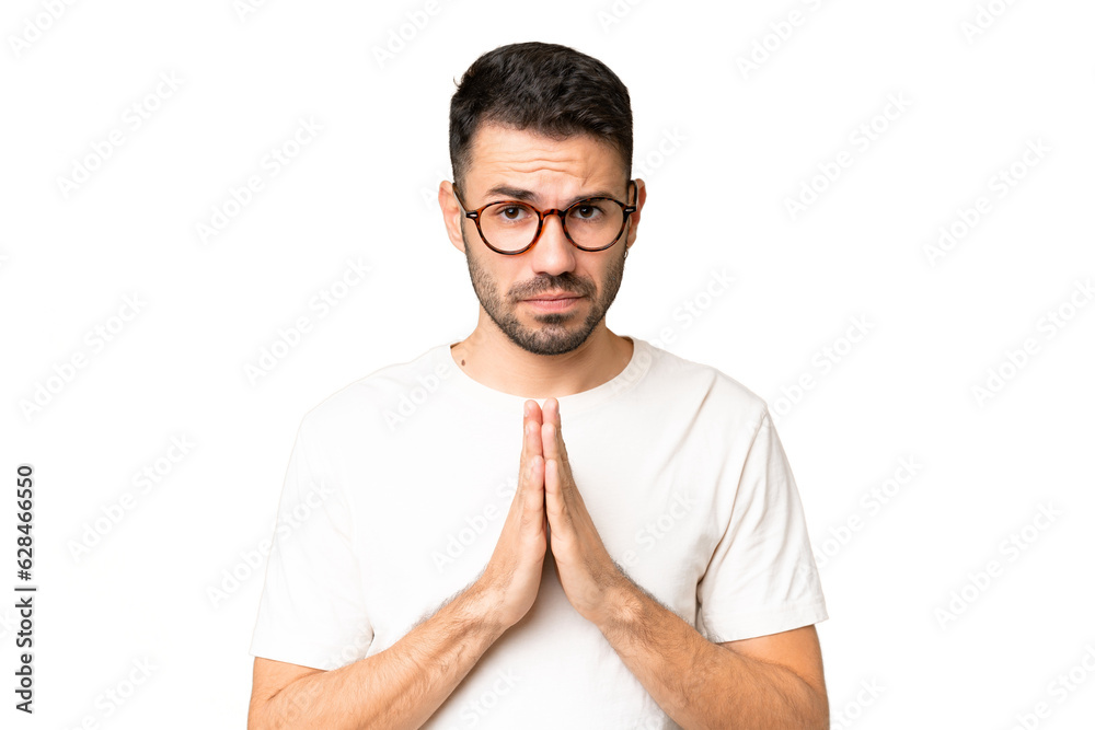 Young handsome caucasian man over isolated chroma key background keeps palm together. Person asks for something Young handsome caucasian man over isolated chroma key background keeps palm together. Person asks for something