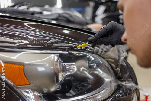 The process of installing a protective polyurethane film for paint on the front headlight of a car. © Dmitry Presnyakov