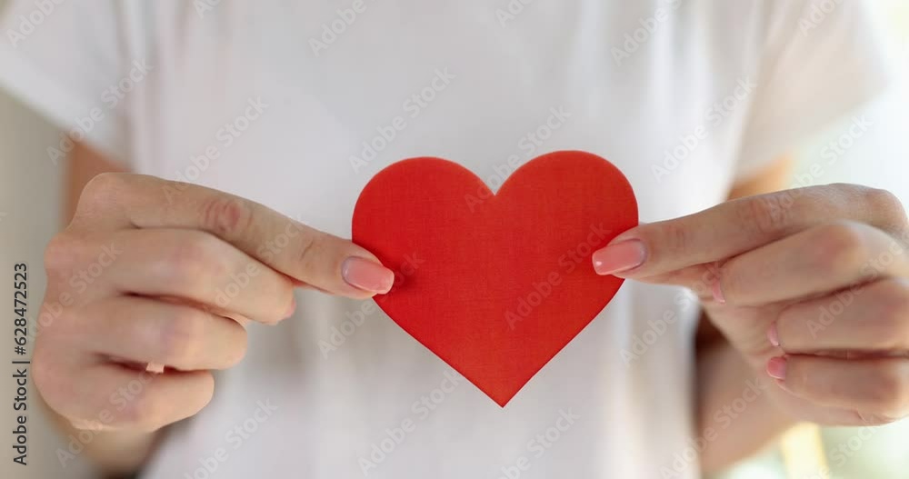 Female hands hold red paper heart closeup. Valentine card volunteering and donation Female hands hold red paper heart closeup. Valentine card volunteering and donation
