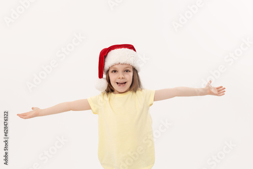 Portrait of surprised and shocked little toddler child girl in Santa hat standing over white background. Looking at camera. Happy New Year and Christmas holiday concept