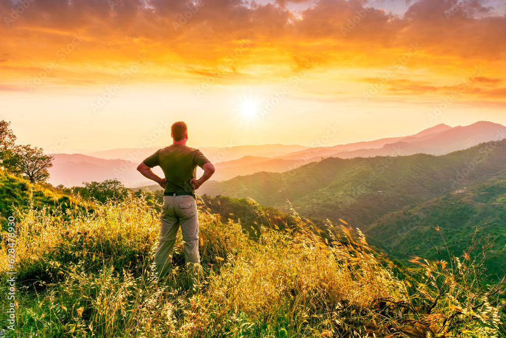 rejoicing man with beautiful scenic mountain sunset landscape on background. happy man watching amazing evening sunset rejoicing man with beautiful scenic mountain sunset landscape on background. happy man watching amazing evening sunset