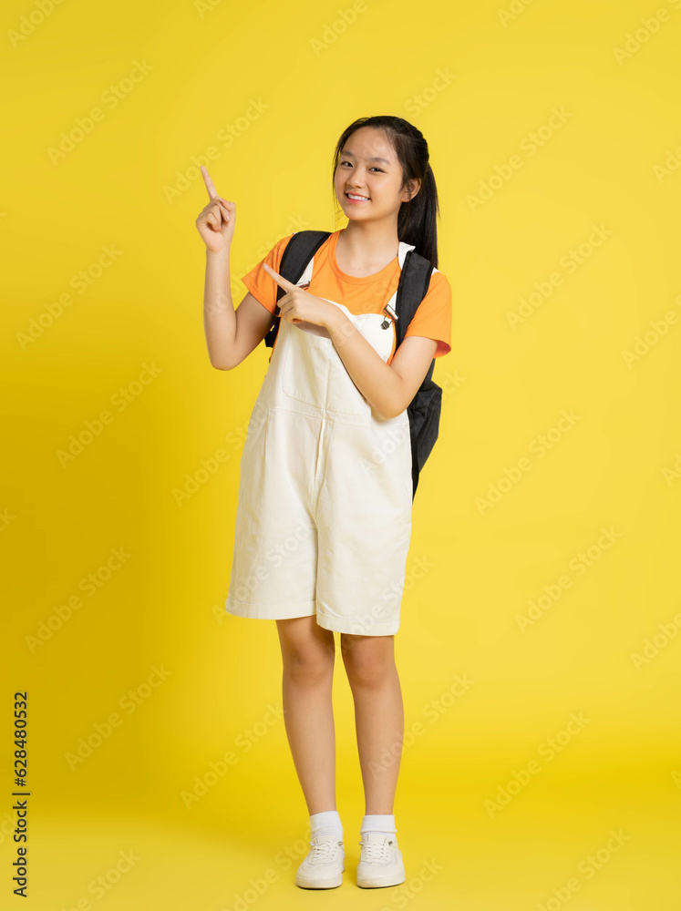 portrait of beautiful asian schoolgirl wearing a backpack on a yellow background. portrait of beautiful asian schoolgirl wearing a backpack on a yellow background.