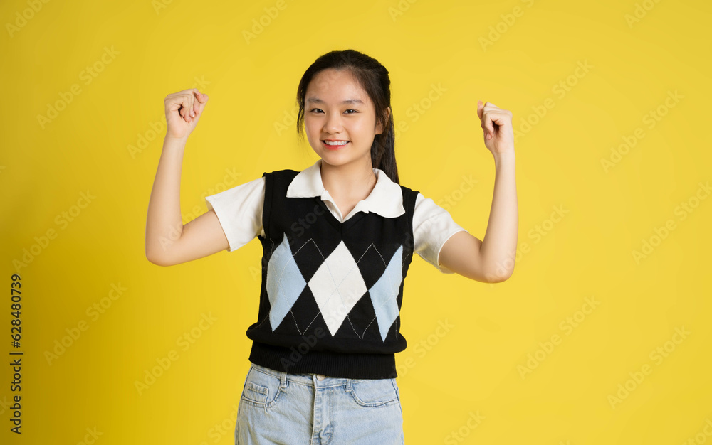 Portrait of a beautiful asian girl posing on a yellow background Portrait of a beautiful asian girl posing on a yellow background