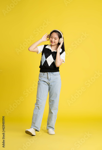 fullbody image of asian girl standing and posing on yellow background