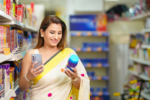 Indian woman using smartphone while shopping in supermarket.
