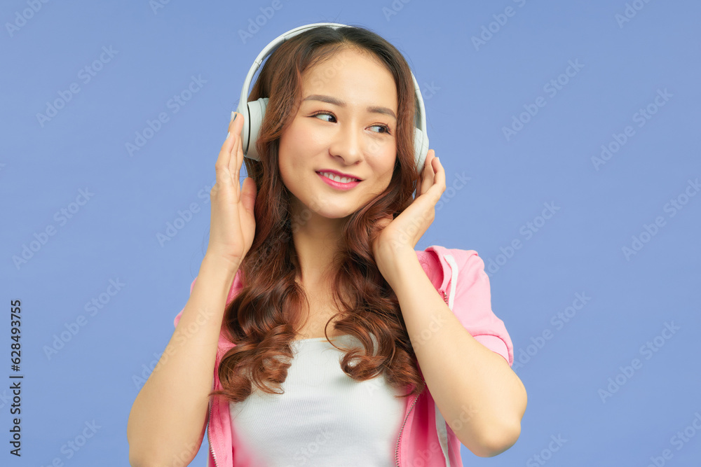 Cute asian young woman in white wireless headphones dancing near copy space Cute asian young woman in white wireless headphones dancing near copy space