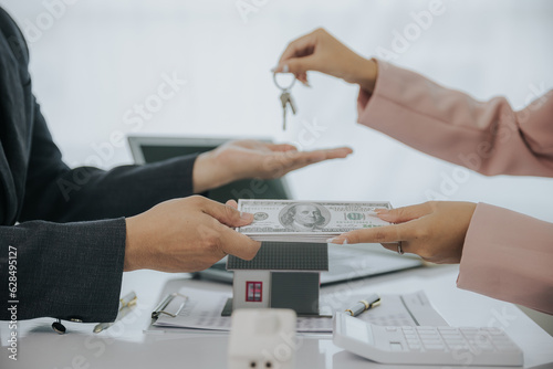 Male businessman or real estate agent holding house key for his client after signing contract in office concept for real estate Moving house or renting property 
