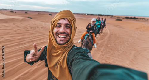 Leinwand Poster Happy tourist having fun enjoying group camel ride tour in the desert - Travel,