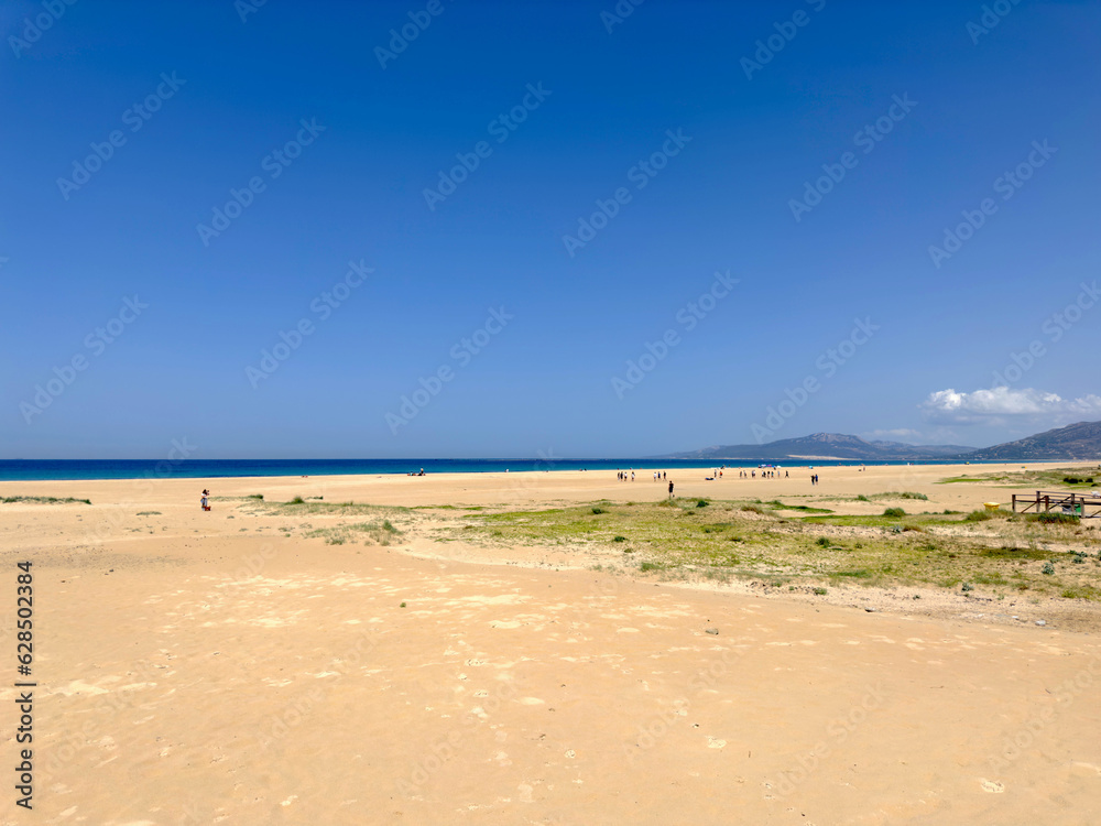 Weitläufiger breiter Sandstrand und Dünen in Tarifa an einem schönen Sommertag und blauem Himmel, Llaya de los Lances, Playa Santa Catalina, Andalusien, Provinz Cádiz, Spanien