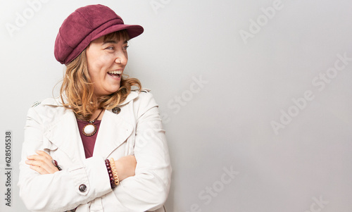 Happy woman with coat and hat looking at the side and laughing