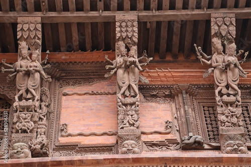 Wooden reapers with elegant carvings of god and and goddess placed in an angles to support the slopped roof of the building in kathmandu, nepal, detailed architecture carving which looks beautiful #628506351