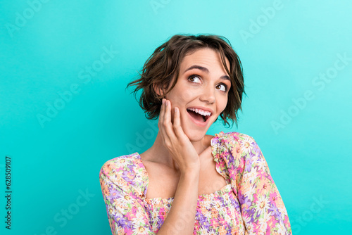 Portrait of astonished creative girl hand touch chin open mouth look empty space isolated on turquoise color background