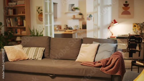 Medium long shot of living room with cozy retro interior with big sofa, wardrobe, table and kitchen in background