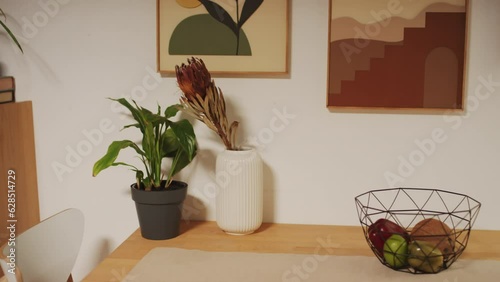 Medium close up of cozy dining place with table and chaires for family , plants on table and retro posters above it in apartment photo