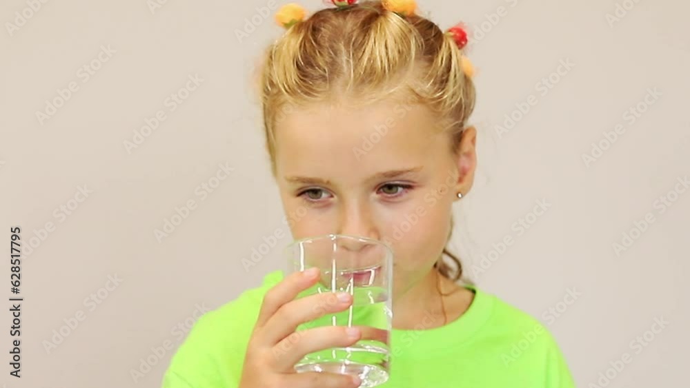 Little girl drinks clean water from a transparent glass Little girl drinks clean water from a transparent glass