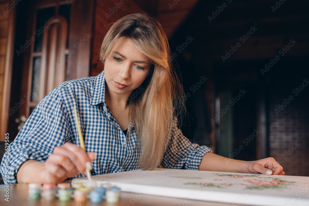 Fototapeta premium A young woman is painting a picture. The background is blurred. Art concept.