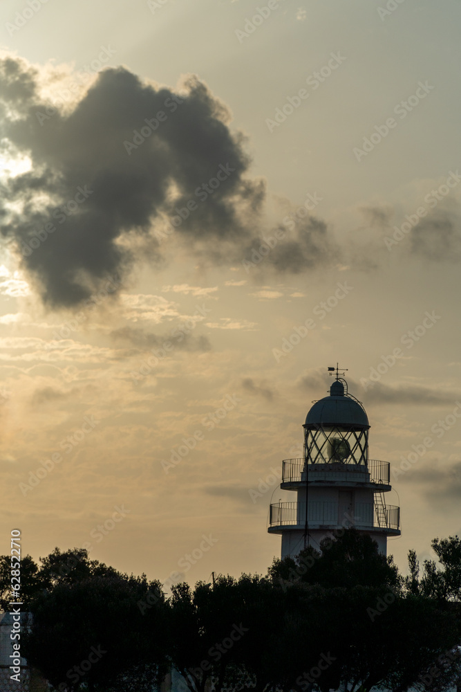 Silhouette of a lighthouse at sunrise with cloudy orange sky