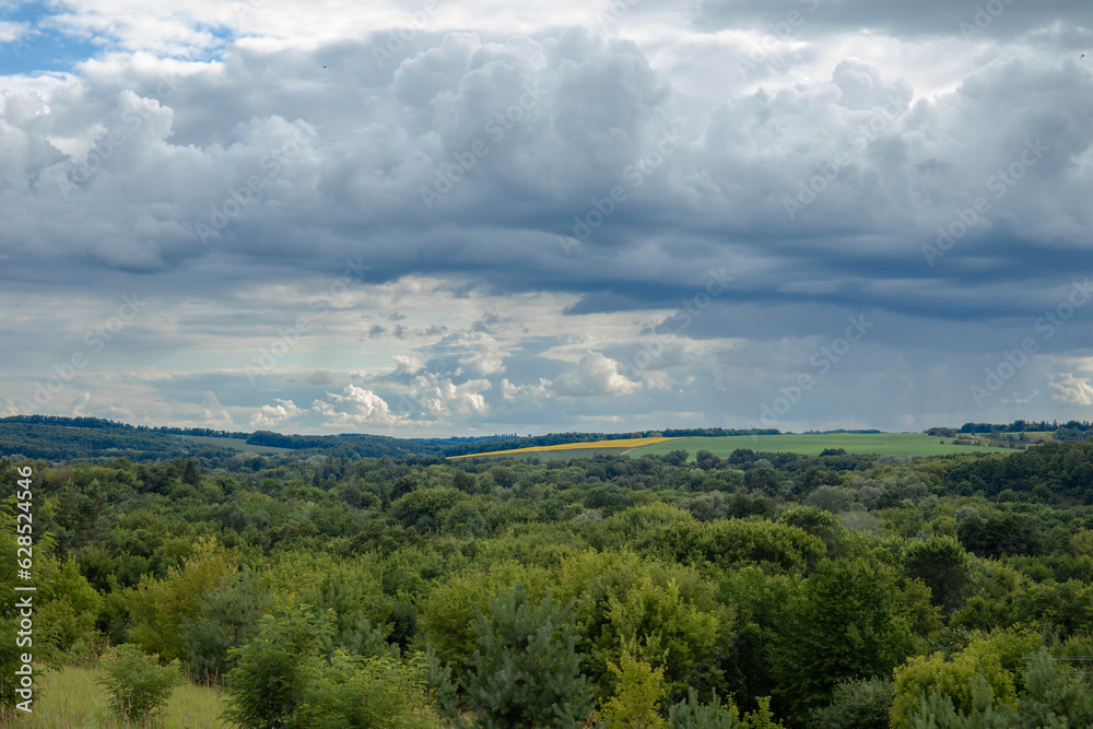 Landscape image of countryside of Ukraine. Cloudy sky, grassy fields and rolling hills rural scenery