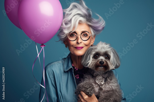 Charming old woman with silver hair with pink air balloons and dog on blue background 