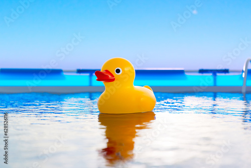Fotobehang A cute yellow rubber duck floats in a blue swimming pool on a sunny day