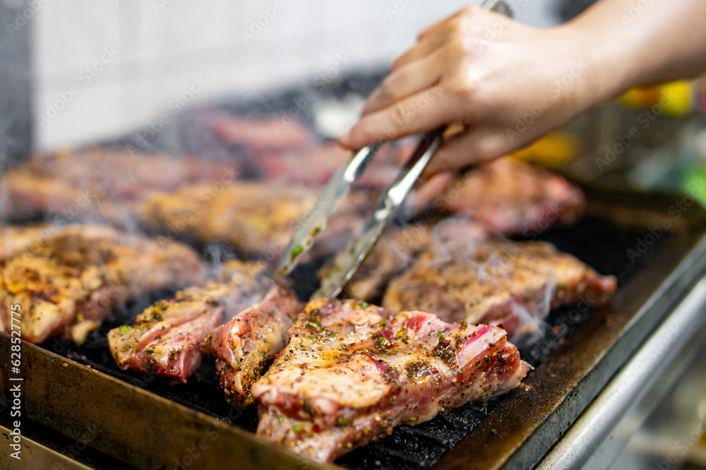 woman chef hand cooking pork ribs on grill in kitchen