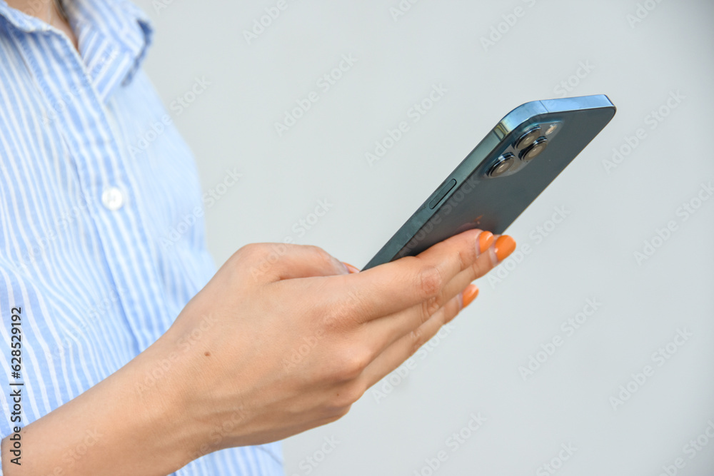 Business woman, holds smartphone in her hands against white wall .