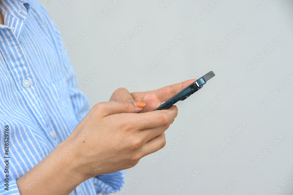 Business woman, holds smartphone in her hands against white wall . Business woman, holds smartphone in her hands against white wall .