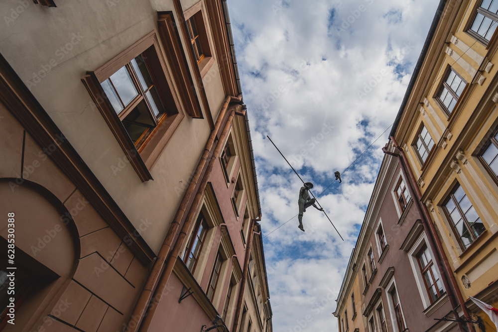 
Tenement houses in Lublin, a rope and a man walking on it. - obrazy, fototapety, plakaty 