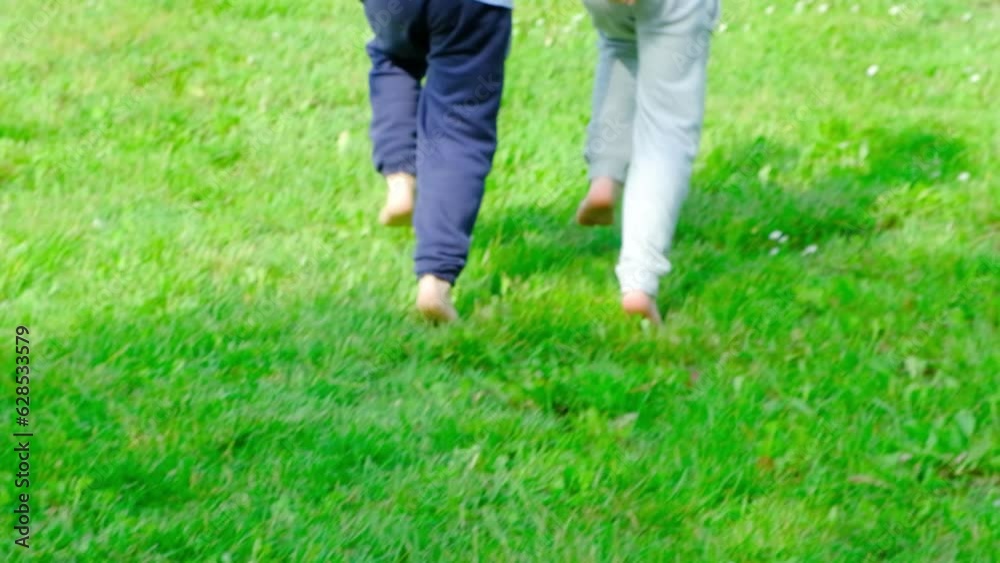A little boy and a girl run barefoot on the grass. The concept of children's friendship and happy childhood A little boy and a girl run barefoot on the grass. The concept of children's friendship and happy childhood