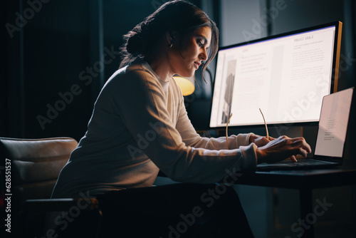 Female entrepreneur typing on a laptop, working overtime in an office photo